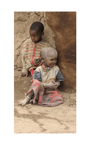 Two African Kids Sitting Near a Rock Wall
